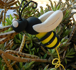 Photo of polymer clay bee in a potted plant.