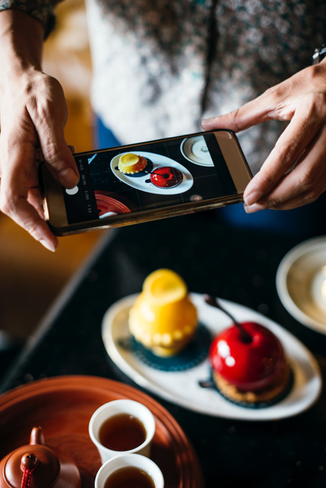 A close up of a person taking a food photography shot with a smartphone 