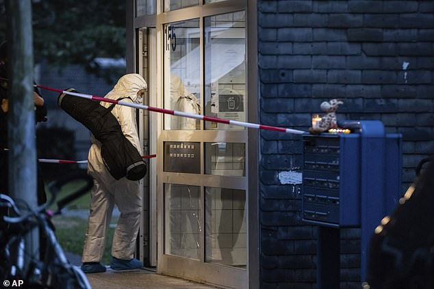 A female forensic investigator enters the apartment building where five children were found dead in Solingen on Thursday