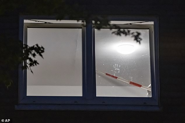 A hand-print is seen in the window of the apartment building where forensic investigators continued working as darkness fell on Thursday
