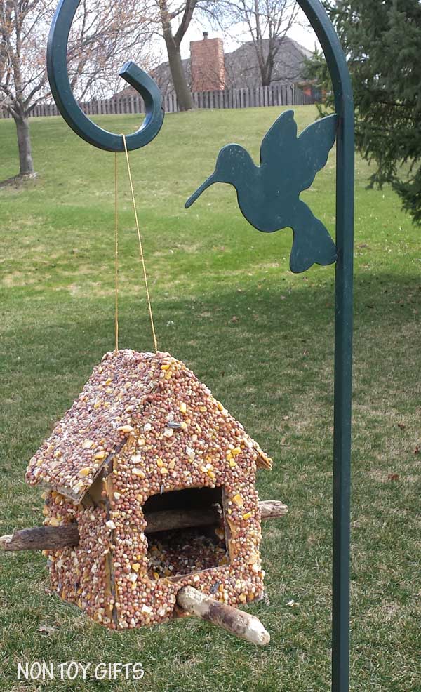 This DIY bird feeder is a fun spring or summer craft to make with kids. You only need a cardboard box, a hot glue gun, two sticks, peanut butter and seeds.