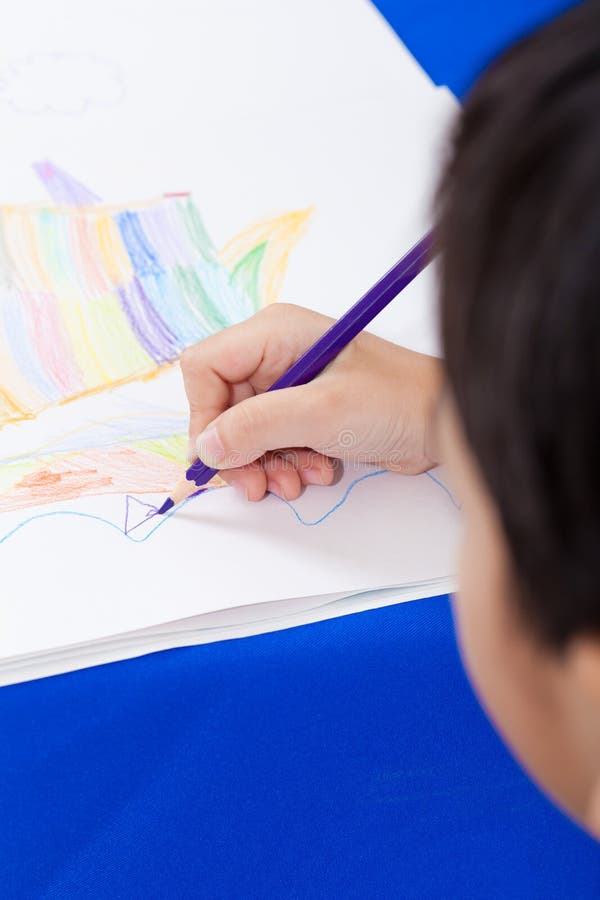 Adorable boy drawing picture. Little asian boy sitting at the table and drawing by colour pencil, shot in studio royalty free stock photo