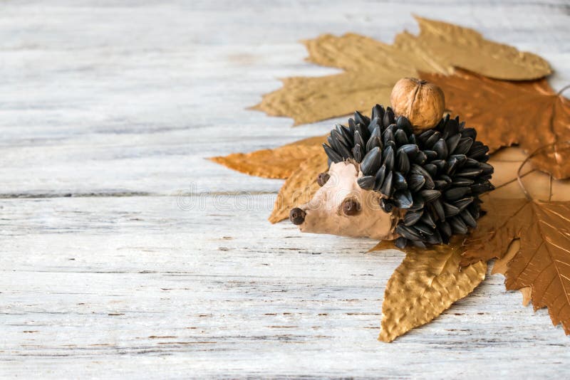 Autumn crafts. Children`s fall crafts and creativity, Hedgehog made from modeling clay, sunflower seeds and nuts. On dry yellow leaves. Ideas for children`s royalty free stock photos