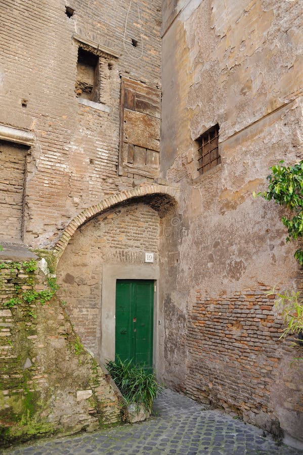 The building is an unusual shape.  courtyard. photo for postcard. Old house with a closed green door. The corner of the building is an unusual shape. Nobody stock photo