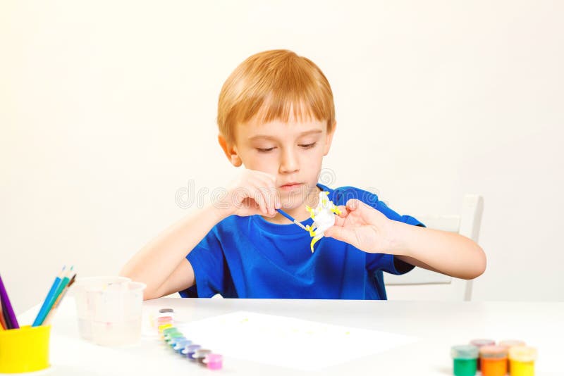 Child painting in art class. Creativity and education concept. Cute little boy paints small figure dinosaur. Children study. Kids. Hobby and creativity stock photos