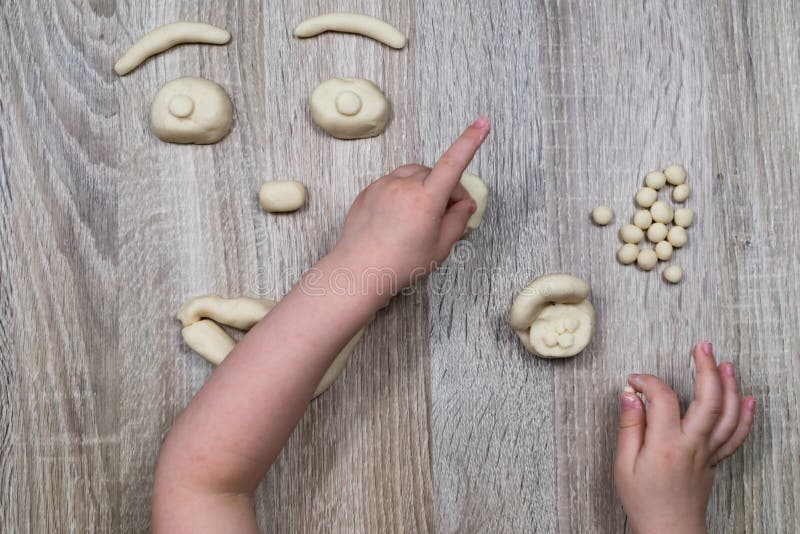 Children`s hands fly figures of salt dough, clay, plasticine on a wooden background. Children`s creativity. Manual stock image