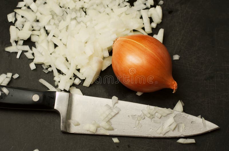 Chopped onions with knife. Kitchen chopping board with chopped and whole onions and a sharp knife royalty free stock images