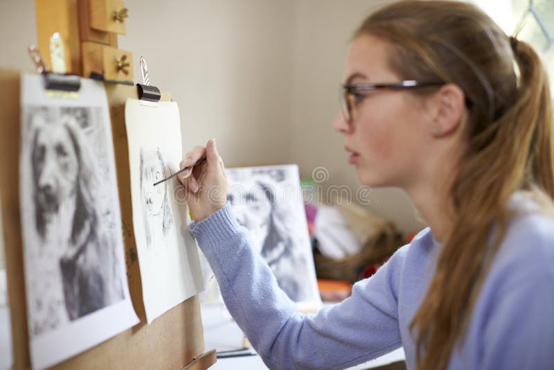 Close Up Of Female Teenage Artist Sitting At Easel Drawing Picture Of Dog From Photograph In Charcoal stock photos