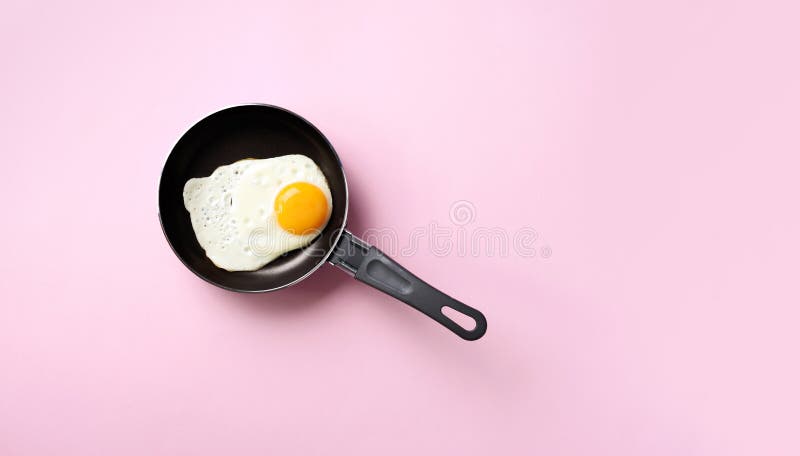 Creative food concept with fried egg on pan over pink background. Top view. Creative pattern in minimal style. Flat lay. Creative food concept with fried egg on royalty free stock photo