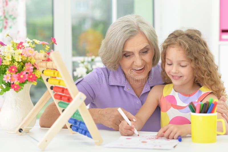 Portrait of cute curly schoolgirl studying with grandmother in her room. Cute curly schoolgirl studying with grandmother in her room royalty free stock photography