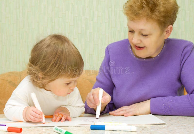 Drawing baby with her grandma. At home royalty free stock photos