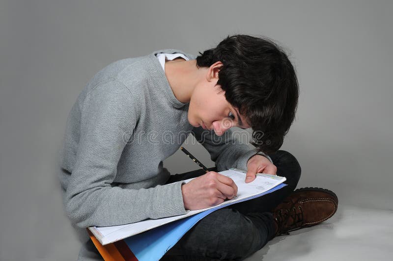 Drawing boy. Teenager boy drawing on a sketch block stock photo