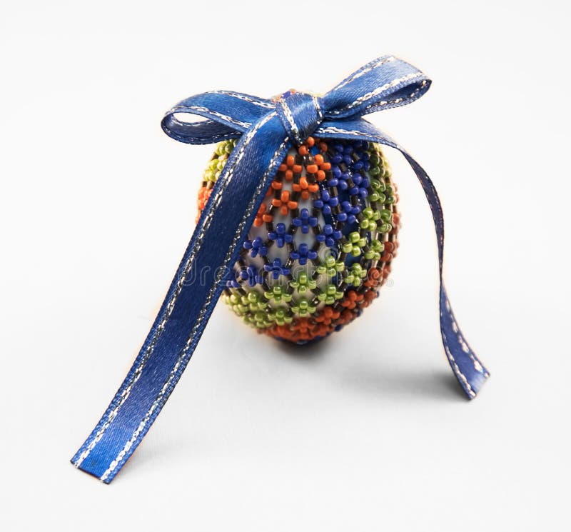 Easter egg. Decorated with glass bead and blue bow royalty free stock image