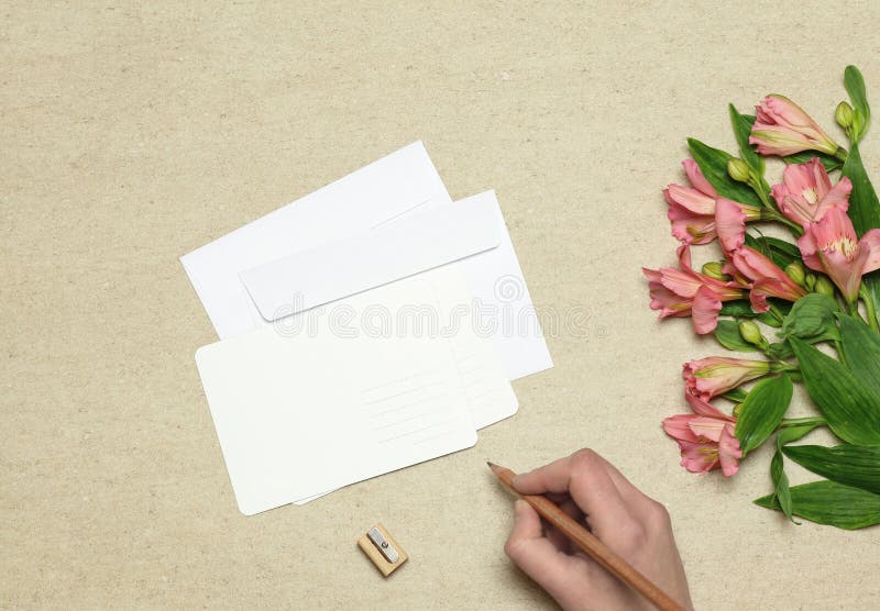 Envelope and postcard with flowers on stone background. Envelope and postcard with pink flowers on stone  yellow background stock photo