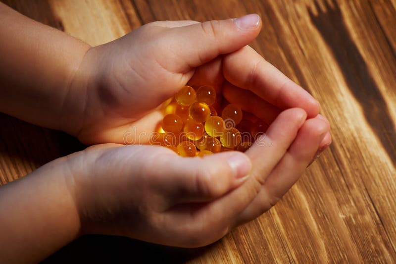 Fish oil capsules in children`s handprints. Close. nutrition and vitamins royalty free stock photography