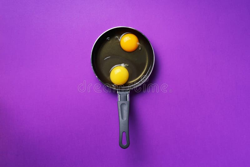 Food concept with two eggs, pan on violet background. Top view. Creative pattern in minimal style. Flat lay. Food concept with two eggs, pan on violet background royalty free stock photography