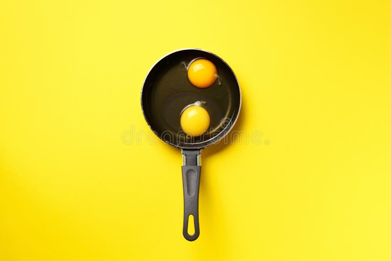 Food concept with two eggs, pan on yellow background. Top view. Creative pattern in minimal style. Flat lay. Food concept with two eggs, pan on yellow background royalty free stock photo