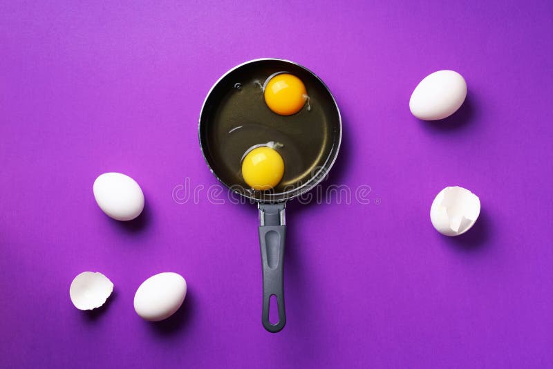 Food concept with two eggs, shells, pan on violet background. Top view. Creative pattern in minimal style. Flat lay. Food concept with two eggs, shells, pan on stock images