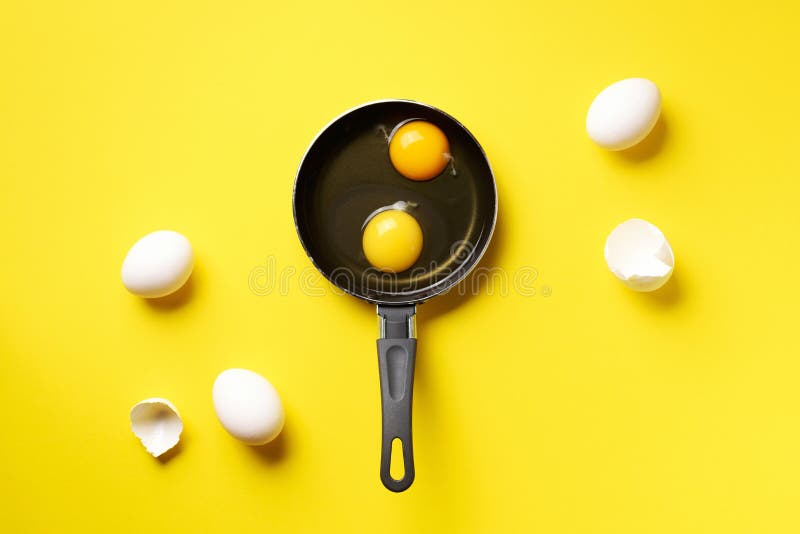 Food concept with two eggs, shells, pan on yellow background. Top view. Creative pattern in minimal style. Flat lay. Food concept with two eggs, shells, pan on royalty free stock photos