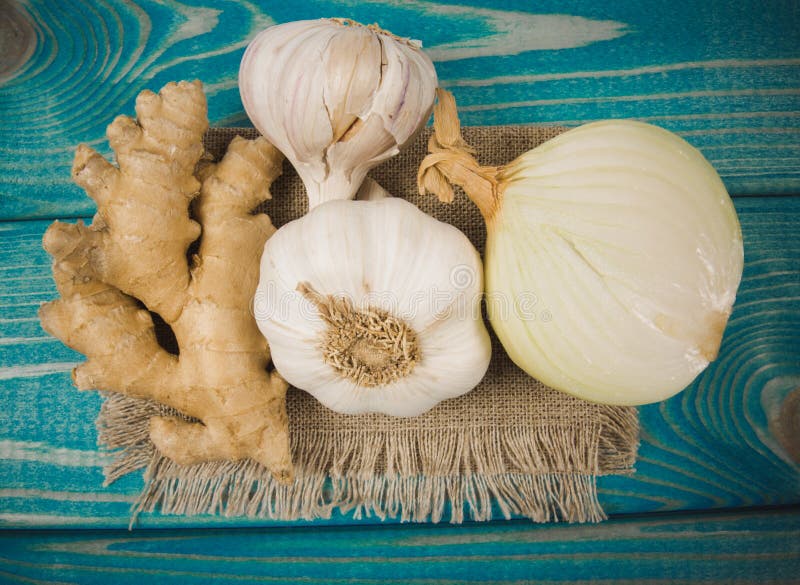 Garlic bulbs, ginger and onion on blue wooden table. Natural medicine. Close up on garlic bulbs, ginger and onion on blue wooden table. Concept of natural stock photo