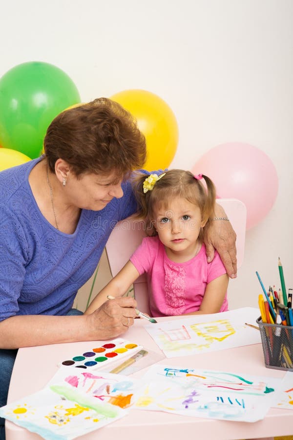 A girl draws with her grandmother. A girl of three years of age draws with her grandmother royalty free stock photography