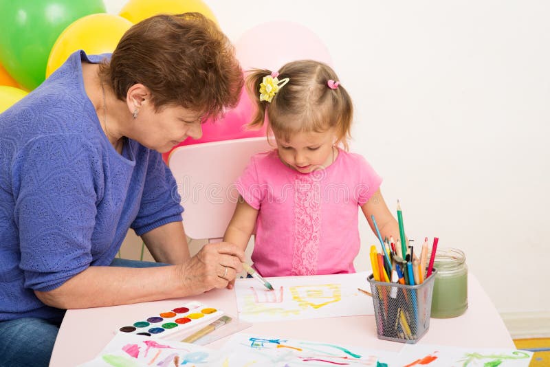 A girl draws with her grandmother. A girl of three years of age draws with her grandmother stock photography