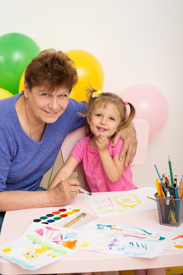 A girl draws with her grandmother. A girl of three years of age draws with her grandmother royalty free stock photography