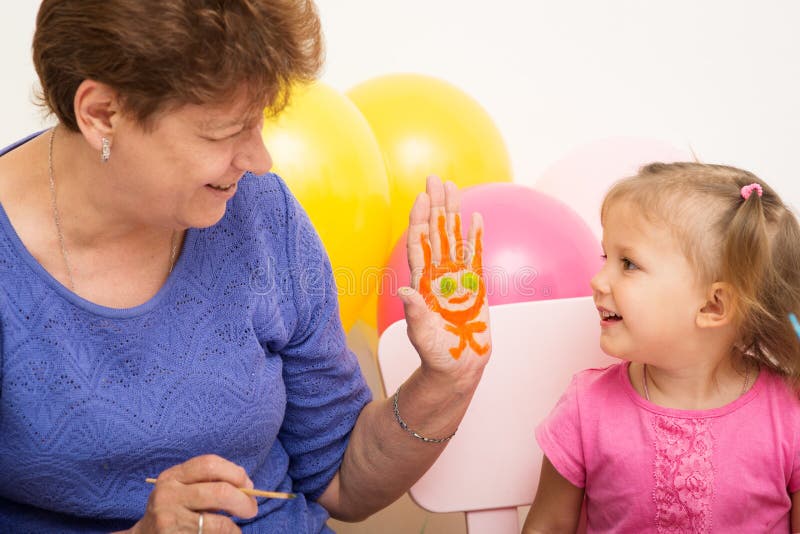 A girl draws with her grandmother. A girl of three years of age draws with her grandmother stock photo