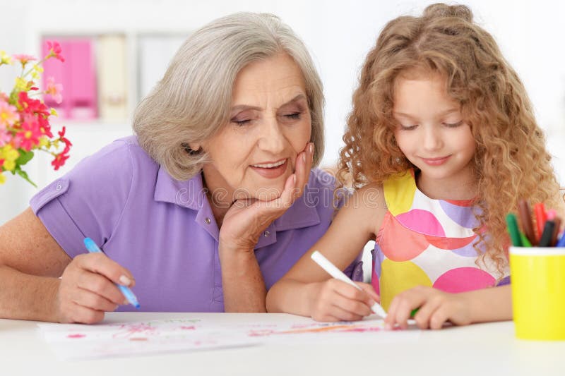 Grandmother with her cute granddaughter drawing. On background royalty free stock photos