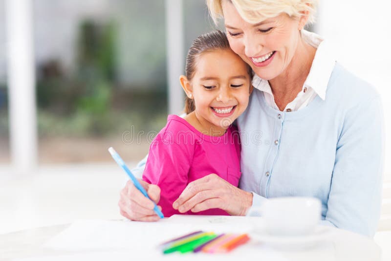 Grandmother teaching granddaughter. Happy senior grandmother teaching her granddaughter how to draw at home stock photos