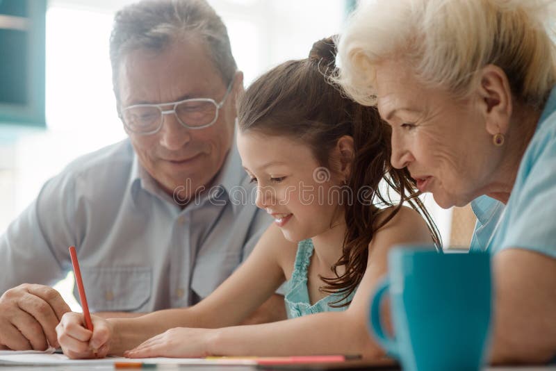Happy girl drawing a picture. For her granny and grandad. Having fun and relax doing a creative activity together royalty free stock image
