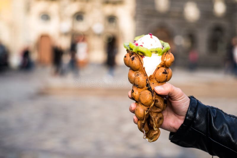 Ice cream in hand. On sunset with old europian city on background stock photos
