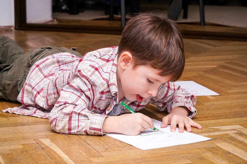 Kid drawing. Young boy drawing on the floor stock photo