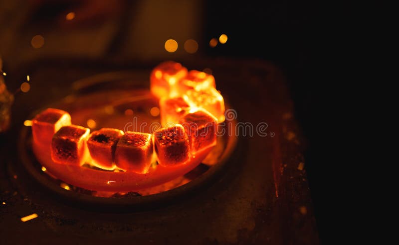 Kindling of square coal for a hookah on a special furnace with a hot spiral royalty free stock image