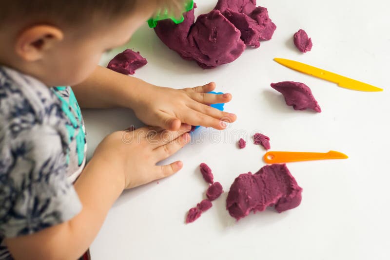 Little boy moulds from plasticine on table, Child hands playing with colorful clay. Little boy moulds from plasticine on table, Child hands playing with stock photography