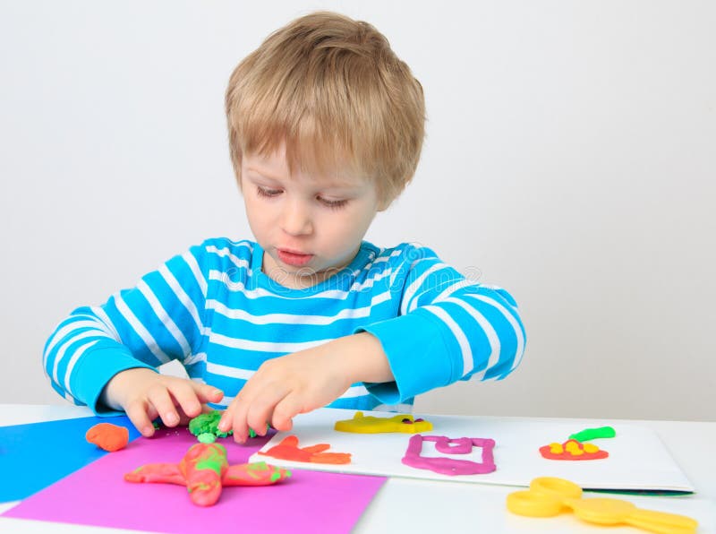 Little boy playing with clay dough stock images
