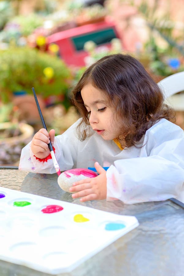 Little Girl Drawing On Stone Outdoors In Summer Sunny Day. Portrait of little child painting, summer outdoor.Kid drawing on a stone royalty free stock image