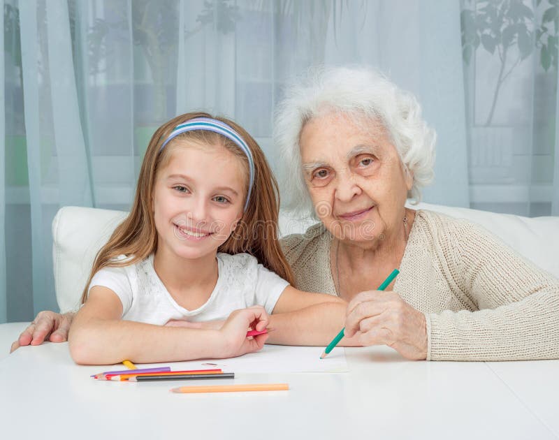 Little girl and her grandmother drawing with. Portrait of little girl with grandmother drawing with pencils royalty free stock photo
