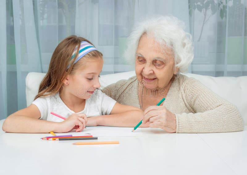 Little girl and her grandmother drawing with. Portrait of little girl with grandmother drawing with pencils stock photography