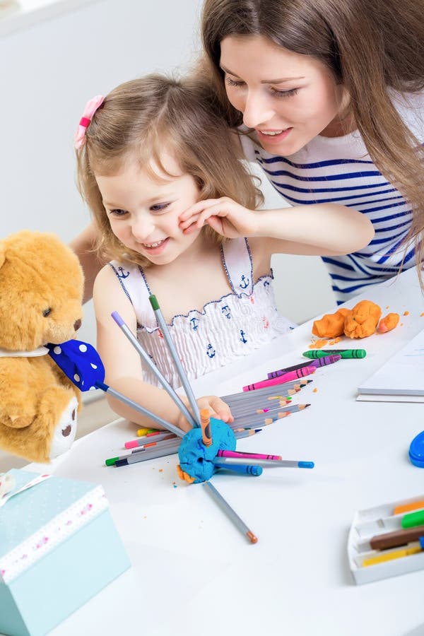 Mom and daughter together. A young mother and her little daughter paint together and made from plasticine and pencils hedgehog. mother and child playing with royalty free stock photos