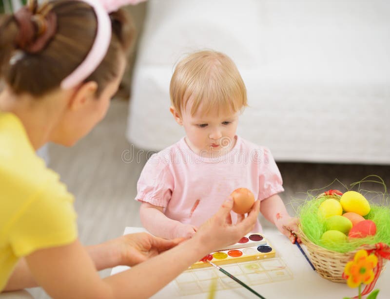 Mother and baby drawing on Easter eggs. In room royalty free stock photos