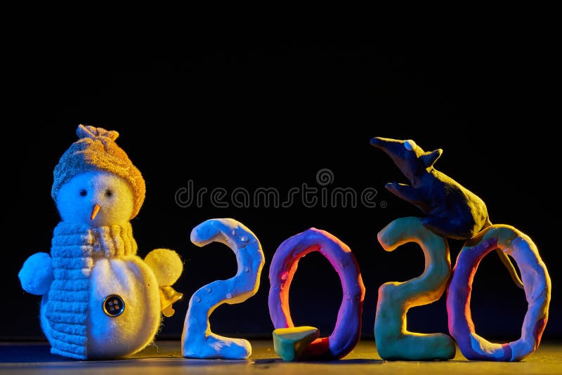 2020 New year design concept. Colored plasticine figures on a black background with mixed light, rat and snowman royalty free stock photo