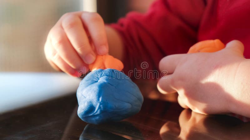 Plasticine hands of the baby play with modelling clay playdought.  stock photos