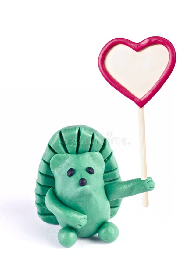 Plasticine hedgehog retaining heart-shaped banner. Isolated over white stock photography