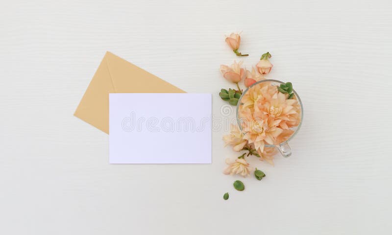 Postcard mockup whith flowers and envelope. On wooden background royalty free stock image