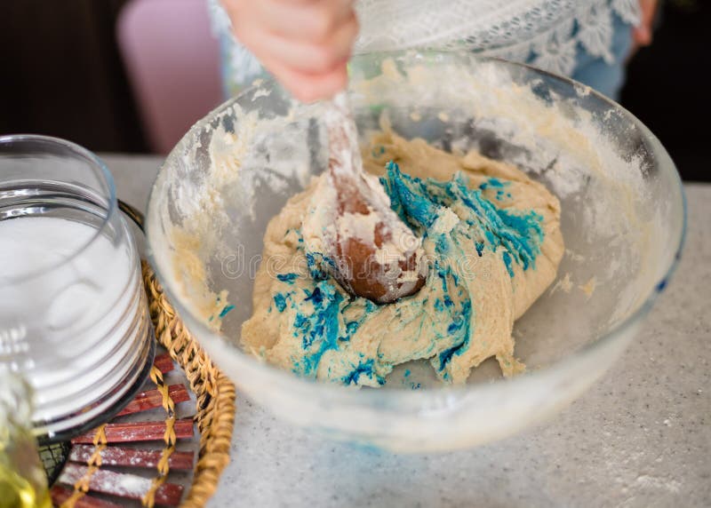 Homemade plastiline. Plasticine. play dough. A preschool girl prepares homemade plasticine from flour, salt and sunflower oil and blue food coloring. The child royalty free stock photo