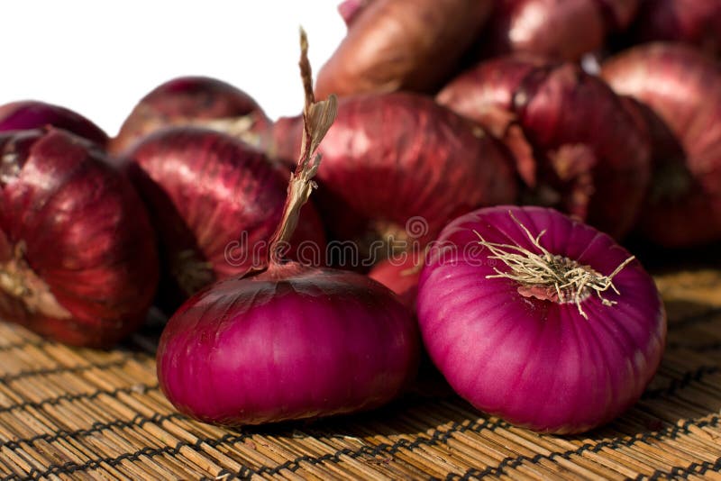 Red onions. Pile of fresh red onions on a bamboo mat royalty free stock images