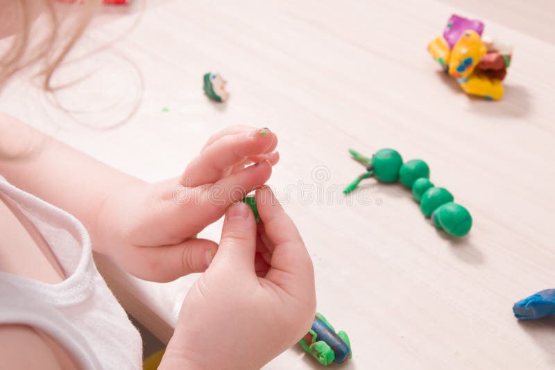 A small child sculpts from plasticine on a wooden table, the development of fine motor skills of hands. Than to occupy a child at home, stay at home royalty free stock image