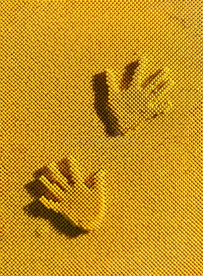 Two handprints on the yellow plastic pinscreen. Trace children`s hands. royalty free stock images