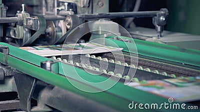 Colourful printed newspapers are getting their edges cut off by a factory mechanism stock footage